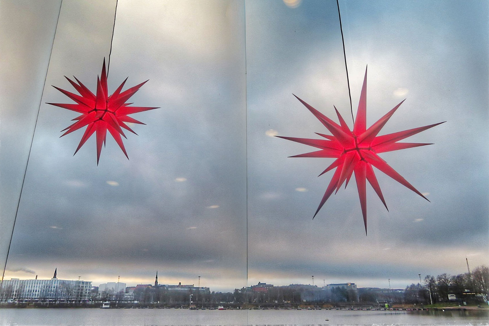 Joulukoristeita ikkunassa, takana harmaa talvimaisema